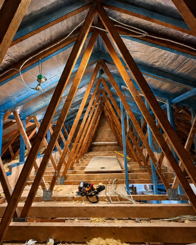 New cabling and a light rough-in run through the timber trusses of a roof space